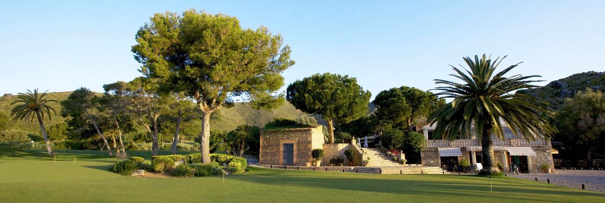 Stone building and pine trees beside the fairway at Capdepera Golf, Mallorca