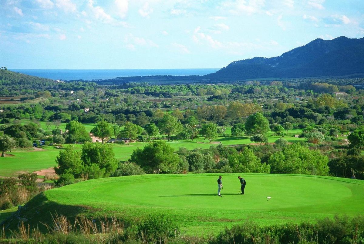 Two golfers on the green with a view of the coast at Capdepera Golf, Mallorca