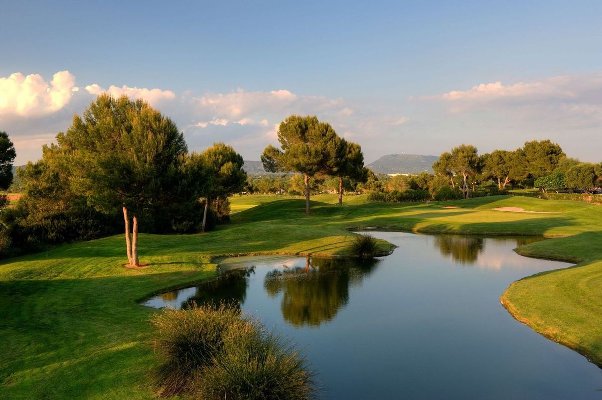 Pond reflecting trees beside the fairway at Son Antem West golf course, Mallorca