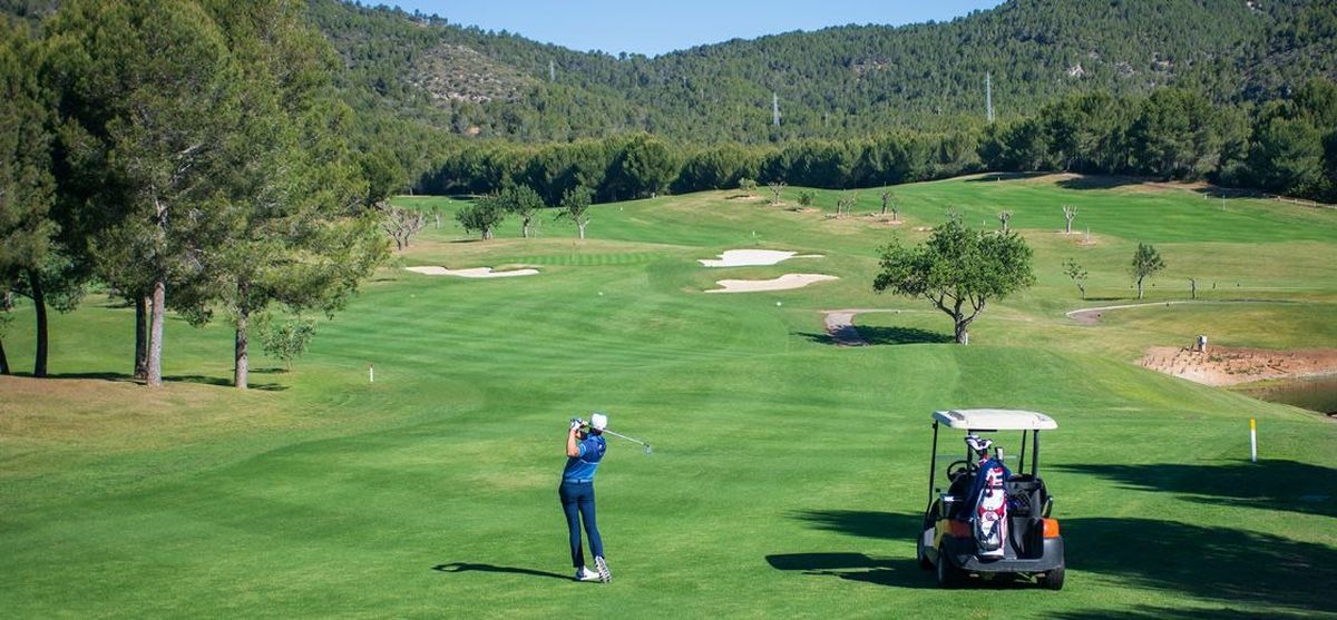 Golfer beim Schlag vom Fairway mit einem Cart in der Nähe – Arabella Golf Son Quint, Mallorca