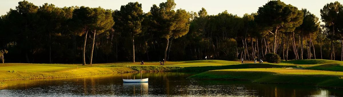 Pond with a rowing boat at sunset among pines at T-Golf Palma Puntiró, Mallorca